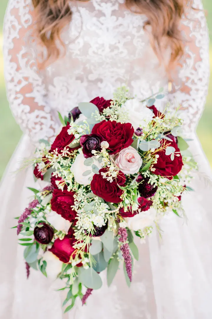 bride holding a bouquet of red, white, and pink roses