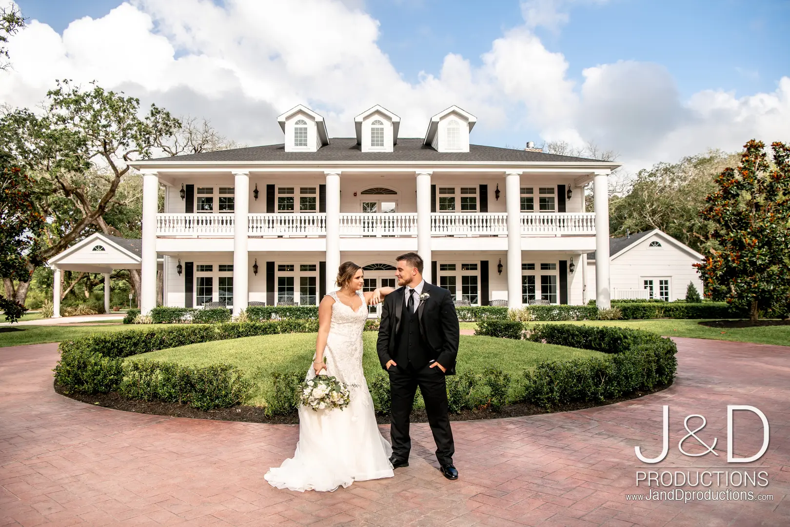 groom and bride standing in front of white building