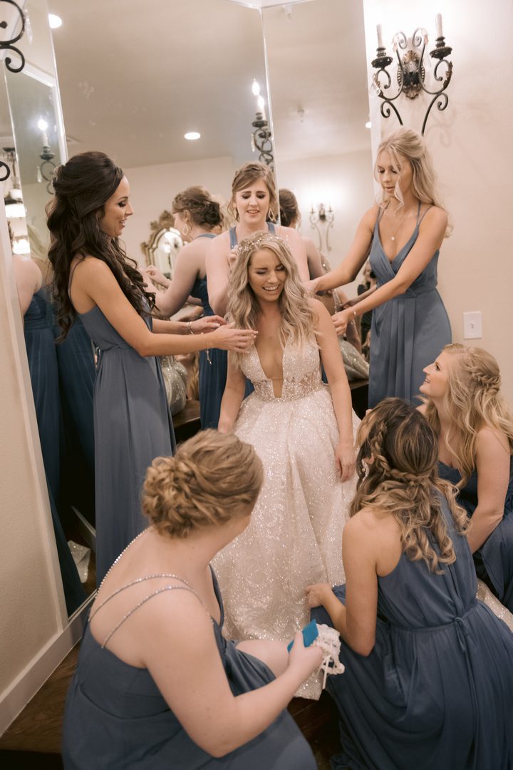 bridesmaids in blue dresses assisting the bride