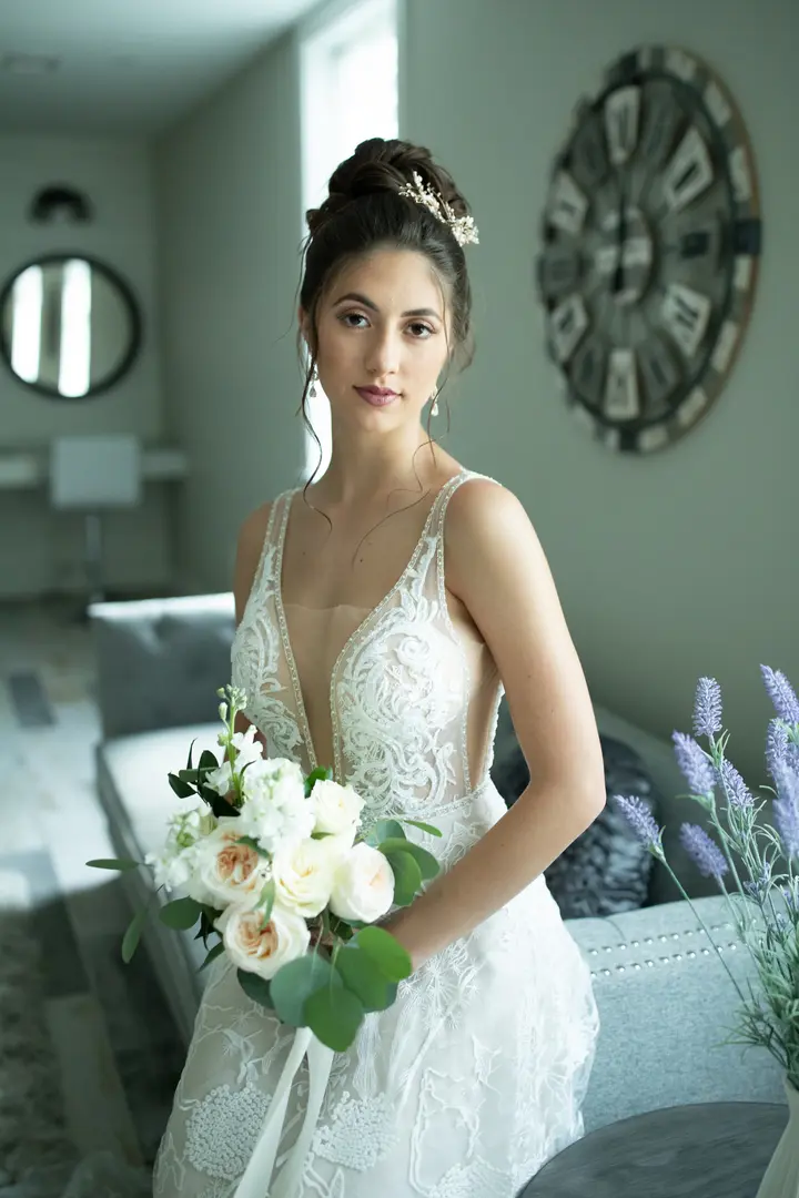 bride sitting on couch and holding white rose bouquet