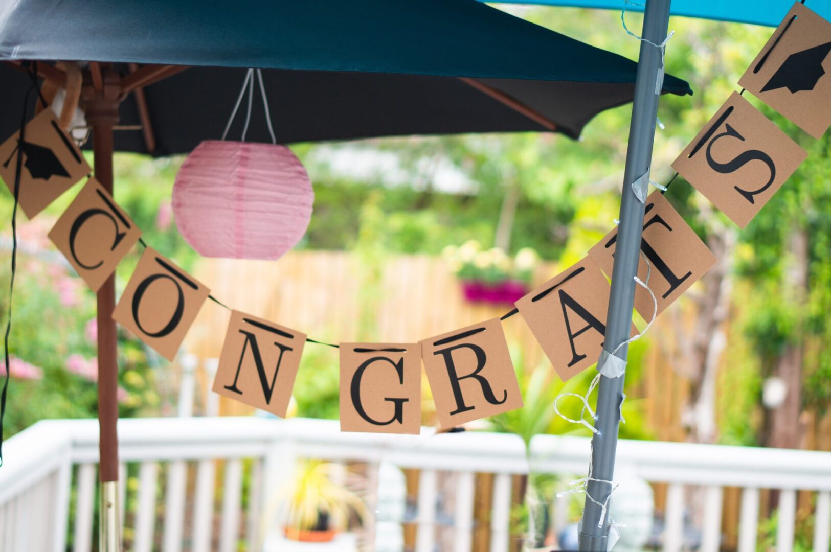 Congrats banner hanged from outdoor table umbrellas